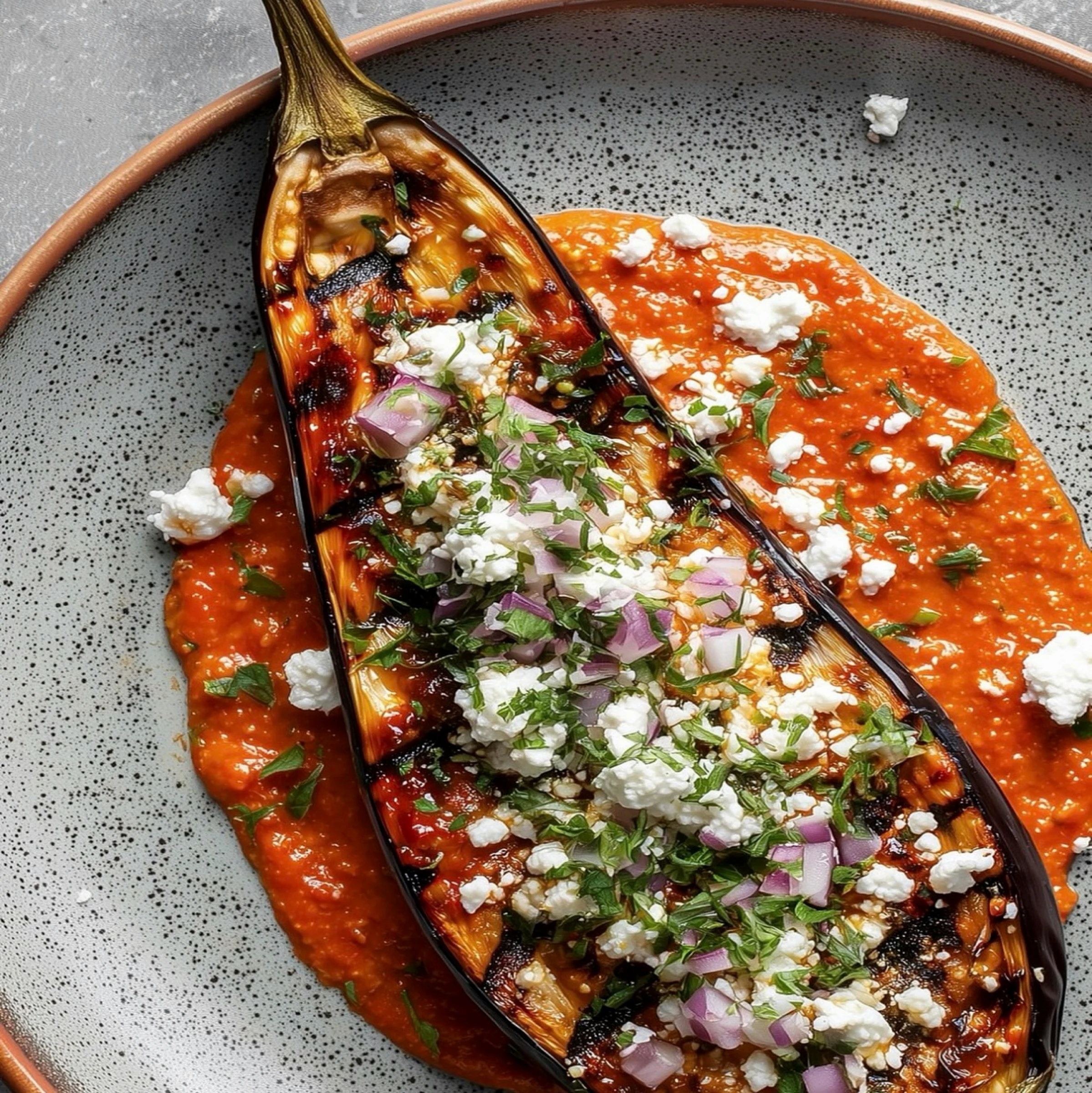 Charred eggplant with red pepper sauce, herbs and cheese